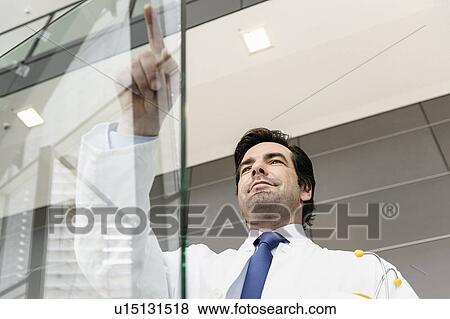 Doctor pointing to glass panel View Large Photo Image Stock Photo - Doctor pointing to glass panel. Fotosearch