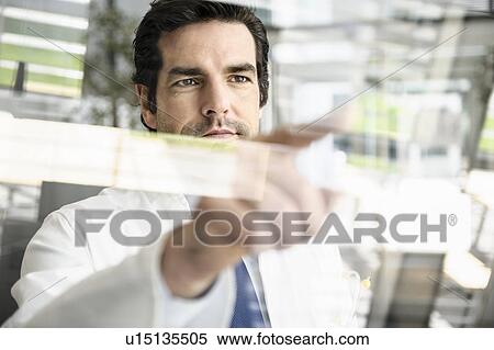 Stock Photography - Doctor pointing to glass panel. Fotosearch