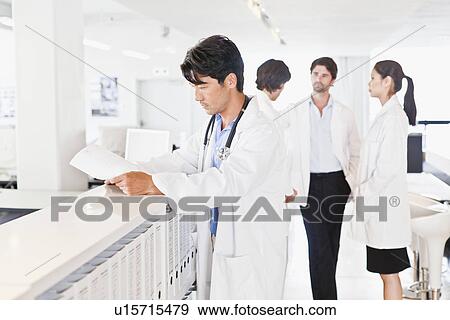 Stock Photo - Doctor reading his notes in hallway. Fotosearch