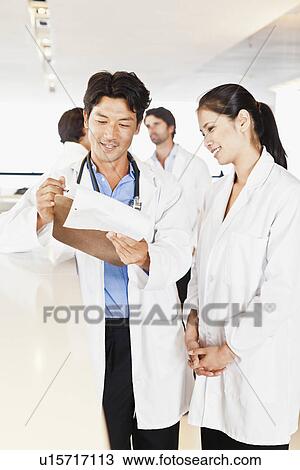 Doctor reading his notes to colleague View Large Photo Image Stock Image - Doctor reading his notes to colleague. Fotosearch