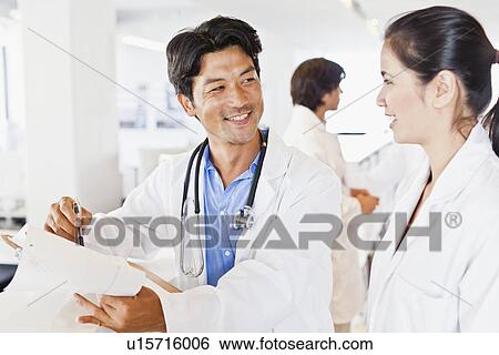 Stock Photograph - Doctor reading his notes to colleague. Fotosearch