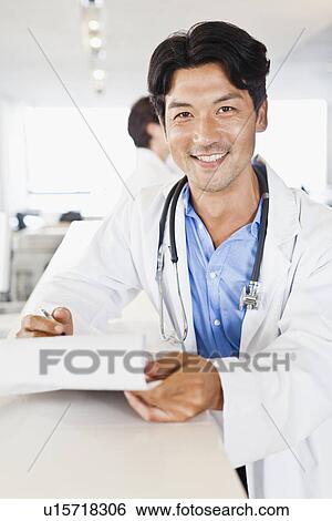 Doctor smiling with folder in hallway View Large Photo Image Stock Photograph - Doctor smiling with folder in hallway. Fotosearch