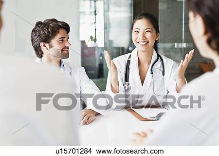 Doctor talking to colleagues in meeting View Large Photo Image Picture - Doctor talking to colleagues in meeting. Fotosearch