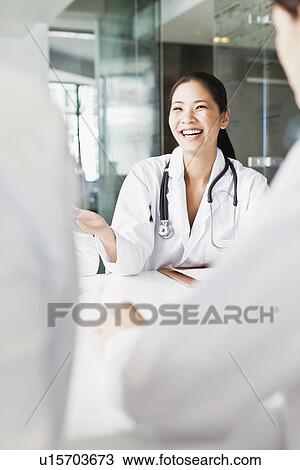 Stock Image - Doctor talking to colleagues in meeting. Fotosearch