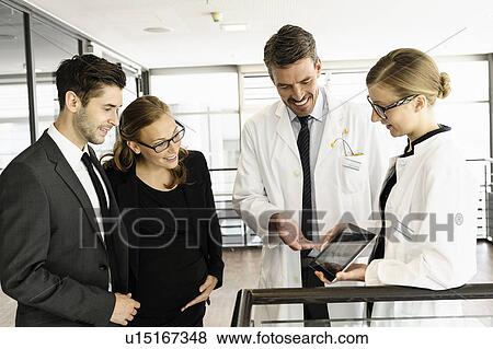 Stock Photo - Doctors and business people with tablet. Fotosearch