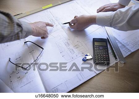 Stock Image - Engineers reading blueprints together. Fotosearch