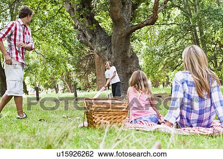 Stock Image - Family relaxing together in park. Fotosearch