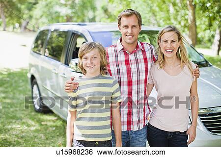 Stock Photograph - Family smiling together by car. Fotosearch