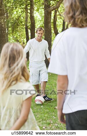 Stock Image - Father and children playing in park. Fotosearch