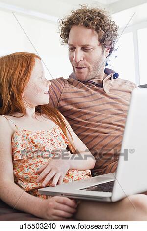 Stock Image - Father and daughter using laptop. Fotosearch