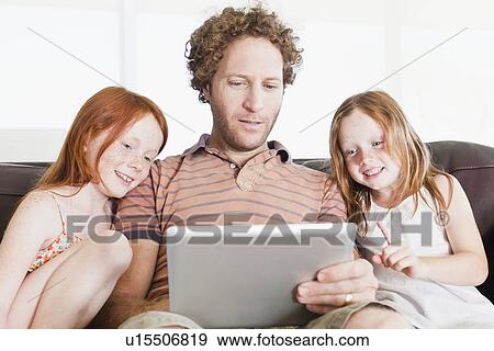 Stock Photo - Father and daughters using tablet. Fotosearch