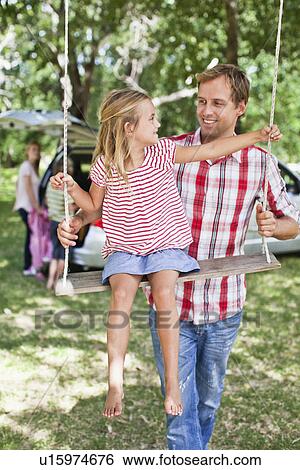 Stock Photograph - Father pushing daughter on swing. Fotosearch