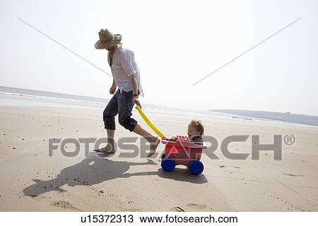 Father with daughter in wagon on beach View Large Photo Image Stock Image - Father with daughter in wagon on beach. Fotosearch