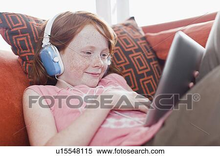Stock Photography - Girl in headphones using tablet computer. Fotosearch