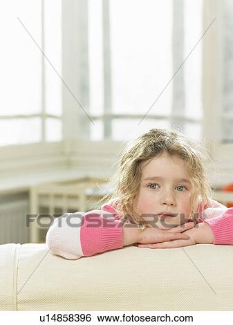 Stock Photograph - Girl leaning on sofa in living room. Fotosearch