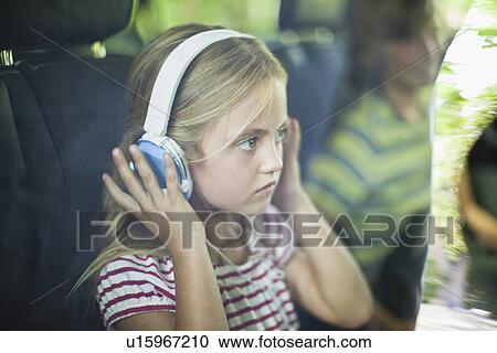 Stock Image - Girl listening to headphones in car. Fotosearch