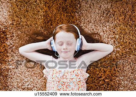 Girl listening to headphones on carpet View Large Photo Image Stock Photo - Girl listening to headphones on carpet. Fotosearch