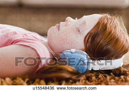Girl listening to headphones on carpet View Large Photo Image Stock Photograph - Girl listening to headphones on carpet. Fotosearch