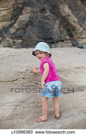 Stock Image - Girl playing in sand on beach. Fotosearch