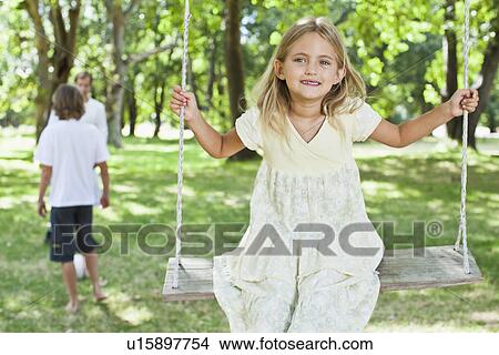 Girl playing on swing in park View Large Photo Image Picture - Girl playing on swing in park. Fotosearch