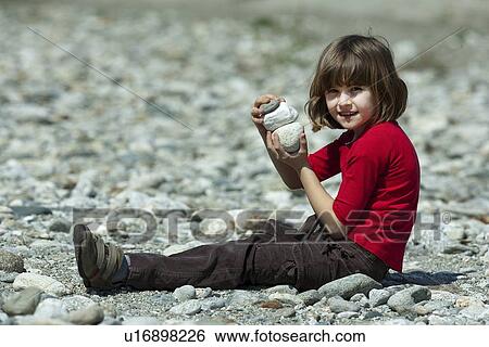 Stock Photograph - Girl playing with rocks on beach. Fotosearch