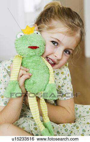 Stock Photograph - Girl playing with toy frog. Fotosearch