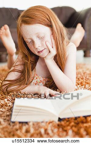 Picture - Girl reading on living room floor. Fotosearch