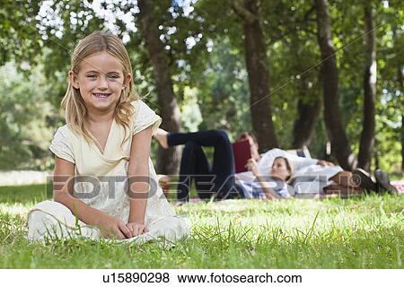 Stock Photo - Girl sitting in grass at park. Fotosearch
