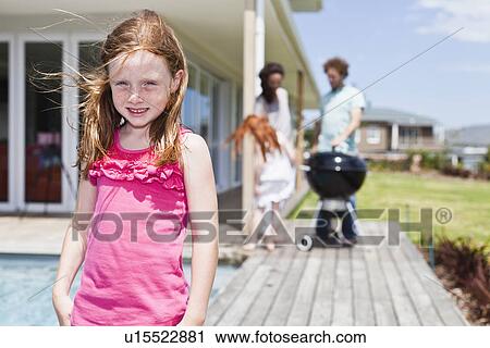 Stock Image - Girl smiling on backyard patio. Fotosearch