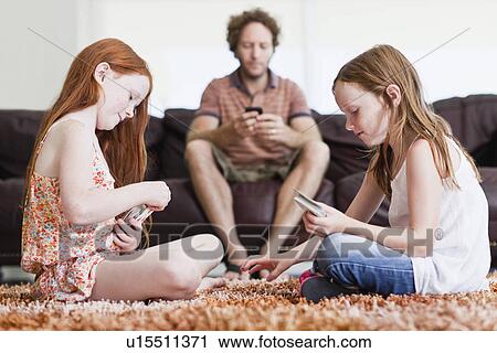 Stock Image - Girls playing cards on living room floor. Fotosearch