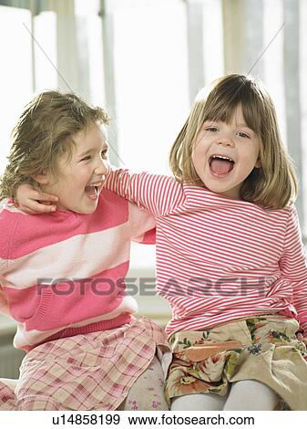 Stock Photo - Girls smiling together indoors. Fotosearch