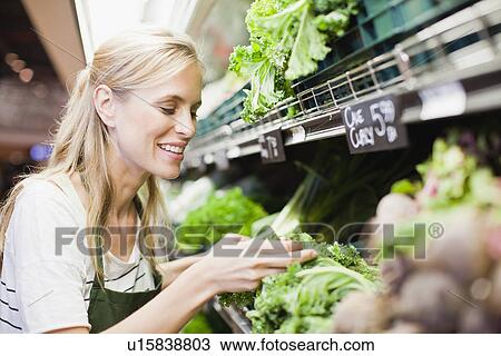 Stock Image - Grocer working in produce section. Fotosearch