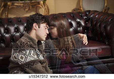 Stock Image - Man holding fading girlfriend on sofa. Fotosearch