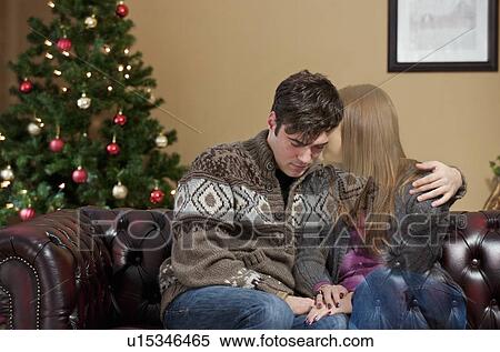 Stock Photography - Man holding fading girlfriend on sofa. Fotosearch