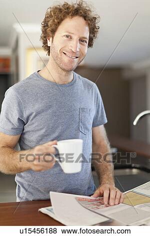 Stock Photo - Man reading newspaper at breakfast. Fotosearch
