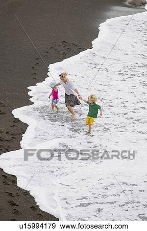 Stock Photo - Mother and children walking in waves. Fotosearch