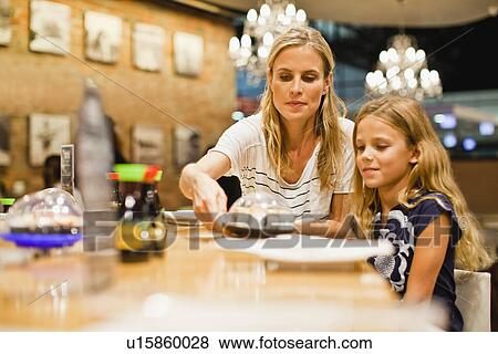 Stock Photo - Mother and daughter eating at restaurant. Fotosearch
