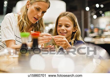 Stock Image - Mother and daughter using chopsticks. Fotosearch