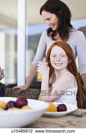 Stock Image - Mother and daughters having breakfast. Fotosearch