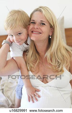 Stock Image - Mother and son hugging on bed. Fotosearch