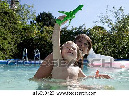 Stock Image - Mother and son playing in swimming pool. Fotosearch