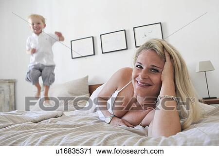 Mother and son relaxing on bed View Large Photo Image Stock Image - Mother and son relaxing on bed. Fotosearch