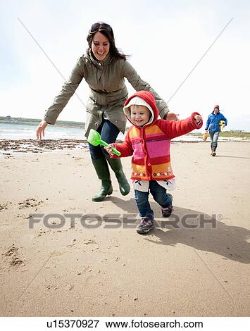 Mother chasing daughter on beach View Large Photo Image Stock Photo - Mother chasing daughter on beach. Fotosearch