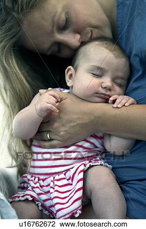 Stock Image - Mother cradling baby girl. Fotosearch