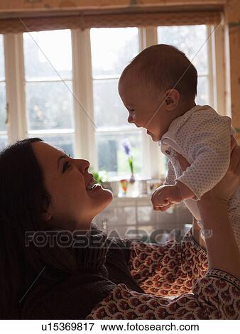 Mother holding baby girl indoors View Large Photo Image Stock Photo - Mother holding baby girl indoors. Fotosearch