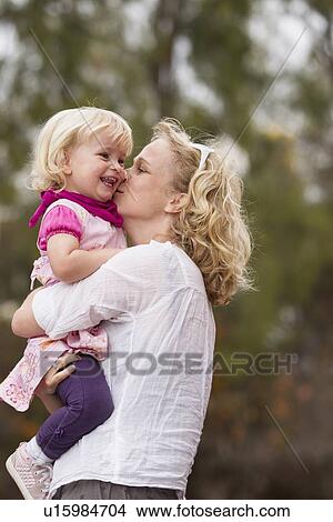 Picture - Mother kissing daughter outdoors. Fotosearch