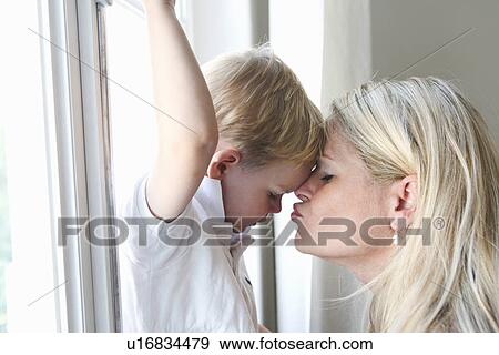 Mother kissing son at window View Large Photo Image Stock Photo - Mother kissing son at window. Fotosearch