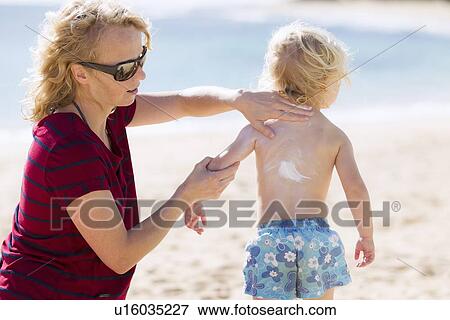 Mother rubbing sunscreen on daughter View Large Photo Image Stock Photo - Mother rubbing sunscreen on daughter. Fotosearch