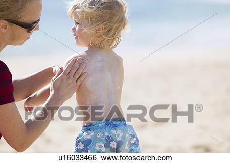 Stock Photograph - Mother rubbing sunscreen on daughter. Fotosearch