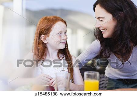 Mother smiling at daughter at breakfast View Large Photo Image Stock Photo - Mother smiling at daughter at breakfast. Fotosearch